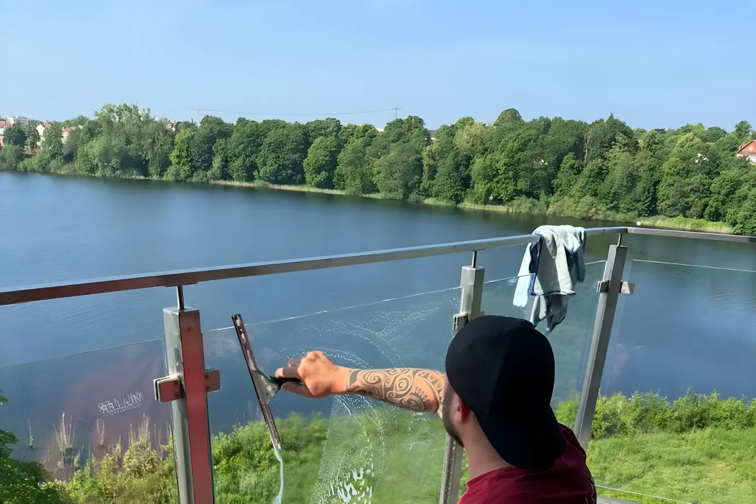 Mitarbeiter von Gebäudeservice Müller reinigt eine Glasbrüstung mit Blick auf den Schweriner See Mitarbeiter von Gebäudeservice Müller reinigt eine Glasbrüstung mit Blick auf den Schweriner See